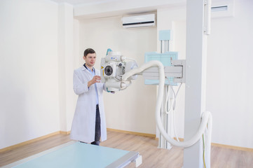  lateral view of a male radiologist adjusting the X-ray machine in examination rom