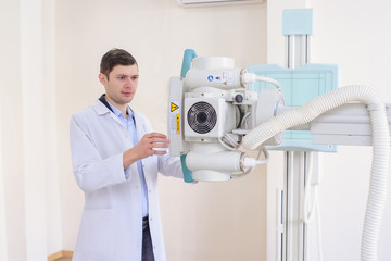  lateral view of a male radiologist adjusting the X-ray machine in examination rom