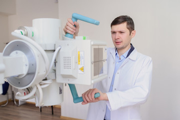  lateral view of a male radiologist adjusting the X-ray machine in examination rom