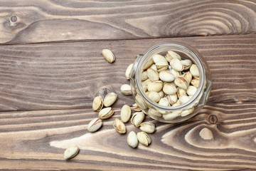 Roasted pistachios in a glass jar. Old wooden background. shallow depth of cut