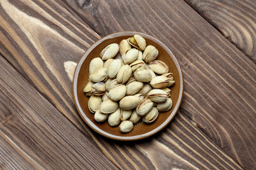 Roasted pistachios on a clay plate. old wood background