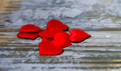 Small red hearts lying together on wooden background with blue and white paint spots. Saint Valentine's day holiday concept. Space for text