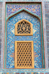 Traditional Arabic mashrabiya window on a tiled wall enclosed with carved wood latticework