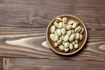 Roasted pistachios on a clay plate. old wood background