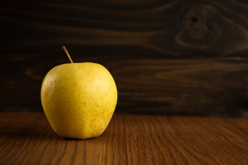 Yellow apple on the wooden vintage background