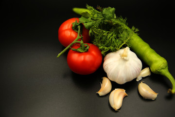 Vegetables on a black background tomato, pepper, onions greens