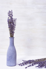 Lavender flowers in blue glass bottle, white wooden background, spa concept, aromatherapy, copy space