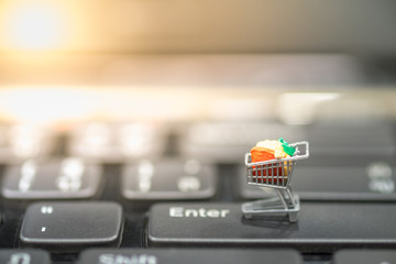 Technology, e-commerce concept. Close up of miniature shopping cart on enter button of computer keyboard.