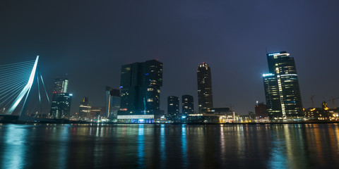 Panoramic view of the Erasmus Bridge and skyline of Rotterdam, Netherlands at night. Famous skyline of Rotterdam with beautiful reflections in the water of the river Maas.