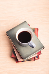 A few books with cup of coffee on wooden floor