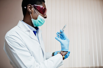 African american doctor in medical mask and red glasses ready to make syringe injection.