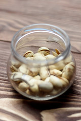 Roasted pistachios in a glass jar. Old wooden background. shallow depth of cut