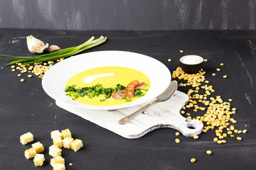 Pea soup with pieces of bacon, parsley and onion in a bowl on a dark background. Pea cream soup.