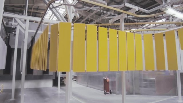 Electrostatic painting. Yellow metal panels move on an overhead conveyor.