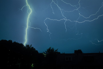 A lightning bolt strikes down to earth. Many small lightning channels can be seen in the air.