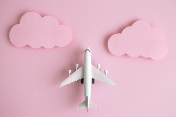 Passenger jet airplane flying through pastel pink clouds abstract.