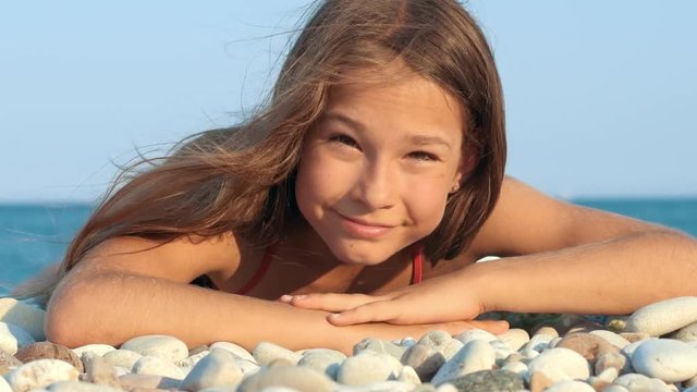 Young girl smiling on sea beach. Portrait of smiling girl lying on pebble beach