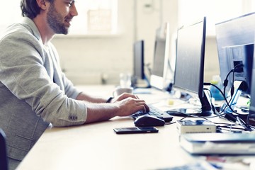 Male office worker looking at computer screen with data