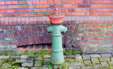 Fire water hydrant.Old fire hydrant on the background of a red brick wall.