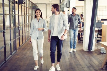 On the way to business meeting. Full length of young modern people in smart casual wear having a discussion while walking through the office.