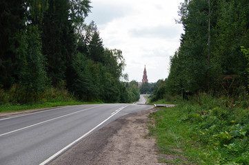 Empty road to the tower with the forest at the sides