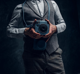 Elegantly dressed young journalist posing with a camera in a studio