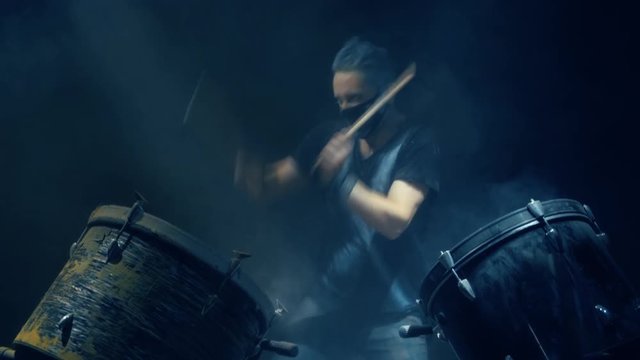 The man is playing snare drum in blue light background.