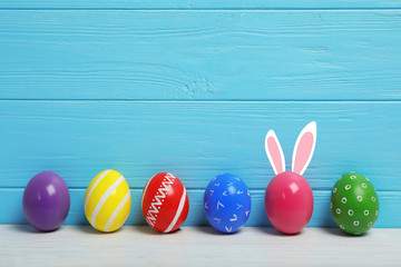 Decorated Easter eggs on table near wooden wall. Space for text