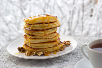pancakes with honey and nuts, a cup of tea, breakfast, view of the winter landscape