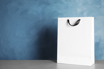 Paper shopping bag on table against color background. Mock up for design