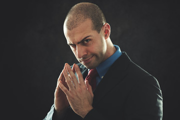 Unscrupolous businessman portrait in a dark background