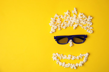 Face made of popcorn and glasses on color background, top view with space for text. Cinema snack