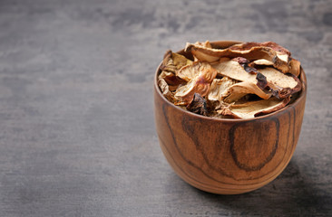 Bowl of dried mushrooms on color background. Space for text
