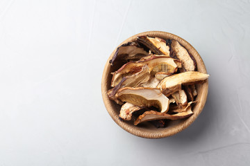 Bowl of dried mushrooms on color background, top view. Space for text