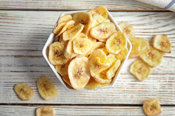 Bowl with sweet banana slices on wooden  table, top view. Dried fruit as healthy snack