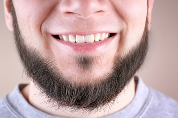 Young man with healthy teeth smiling on color background, closeup