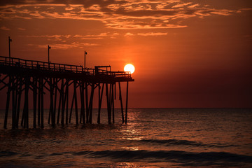 Orange ball of sun at end of fishing pier