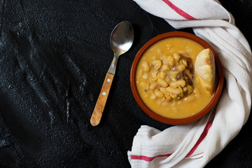 White bean stew, pasulj, bread, traditional Balkan cuisine, black background, top view