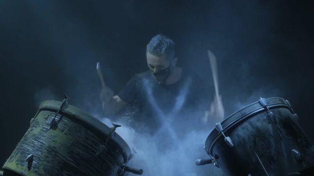 The man is playing snare drum in blue light background.