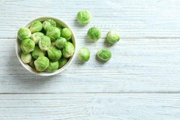 Bowl of fresh Brussels sprouts and space for text on wooden background, top view