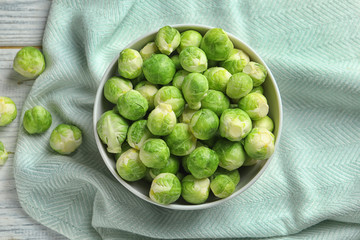 Bowl of fresh Brussels sprouts and fabric on wooden background, top view
