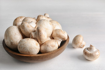 Bowl with fresh champignon mushrooms on wooden table. Space for text