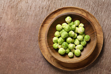 Bowl with fresh Brussels sprouts on wooden table, top view. Space for text