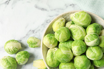 Bowl with fresh Brussels sprouts on marble table, top view. Space for text