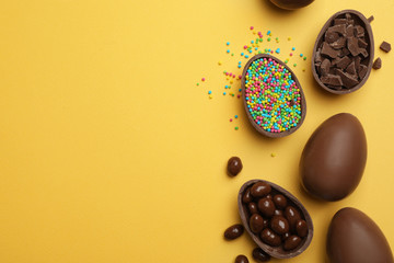 Tasty chocolate Easter eggs on color background, flat lay with space for text