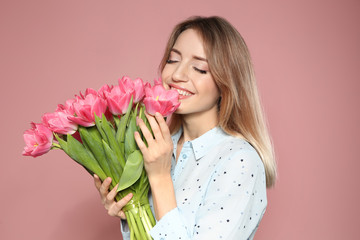 Portrait of beautiful smiling girl with spring tulips on pink background. International Women's Day