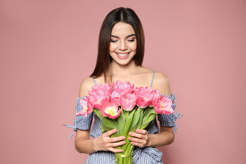 Portrait of beautiful smiling girl with spring tulips on pink background. International Women's Day