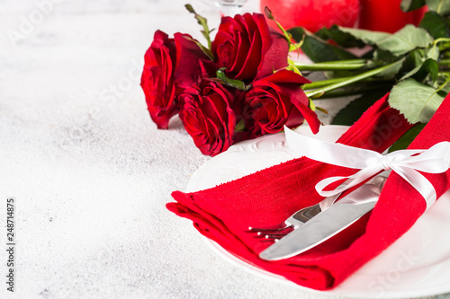 Holiday table setting with plate, roses and present.