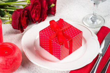 Holiday table setting with plate, roses and present.