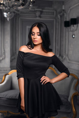 Beautiful girl in a black dress posing in the interior